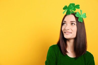 Image of St. Patrick's day party. Pretty woman with green clover headband on golden background. Space for text