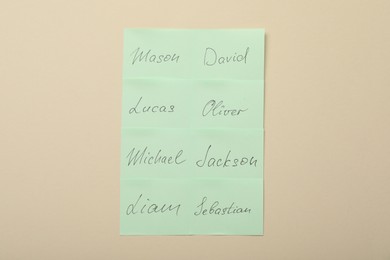 Paper stickers with different names on beige background, top view. Choosing baby's name