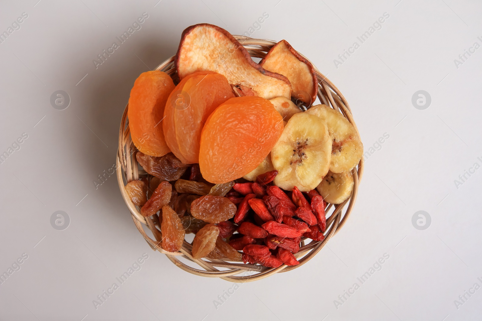 Photo of Wicker basket with different dried fruits on white background, top view