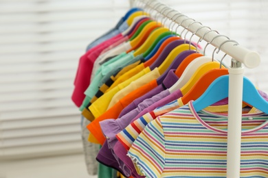 Photo of Different child's clothes hanging on rack indoors, closeup