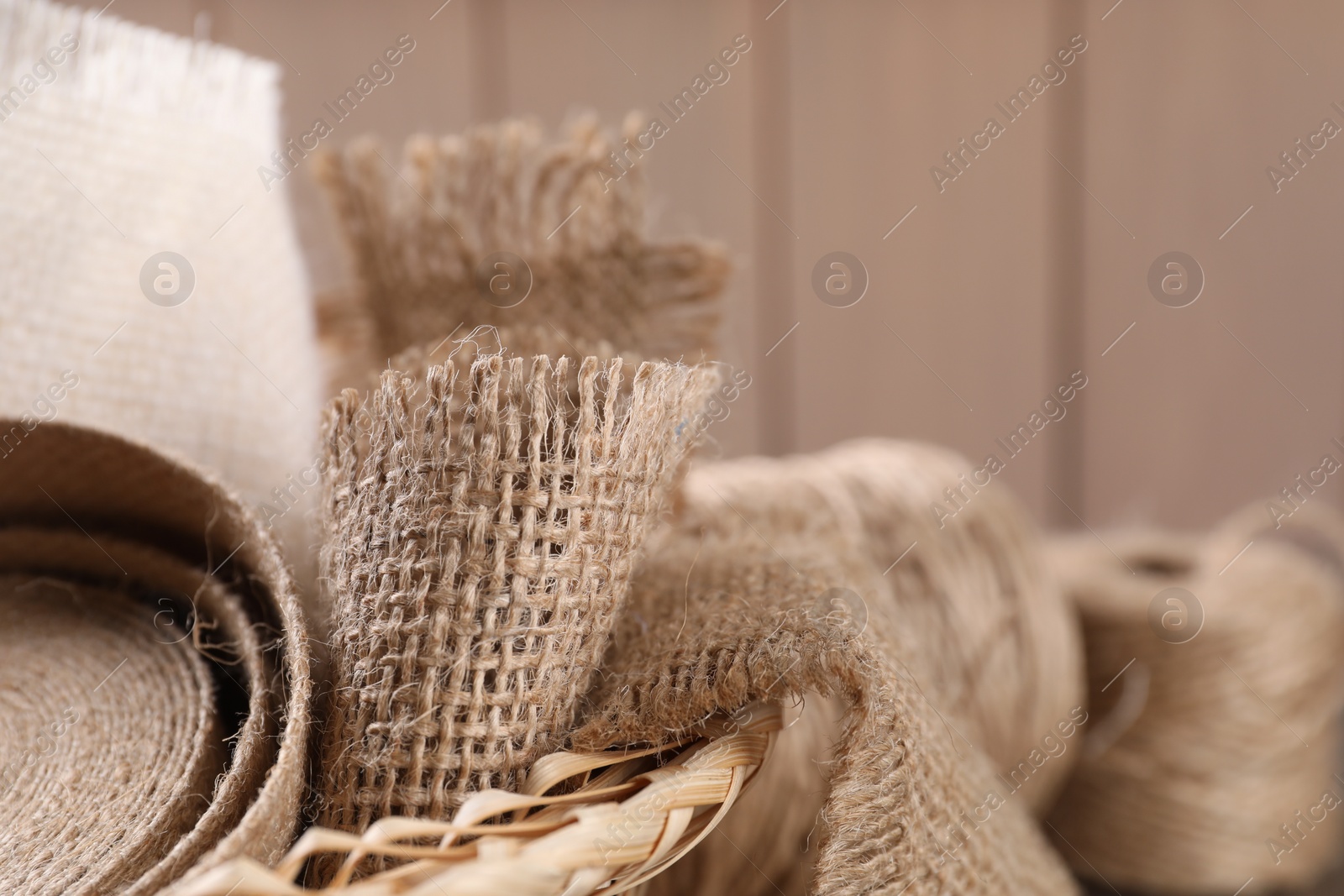Photo of Pieces of burlap fabric in wicker basket, closeup