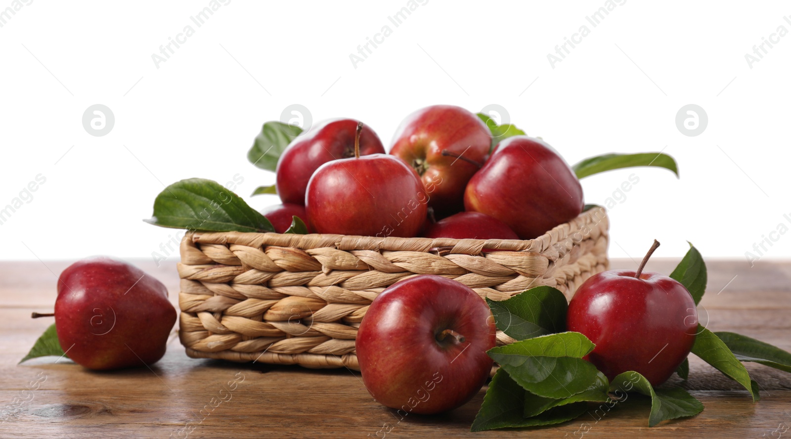 Photo of Fresh red apples and leaves in basket on wooden table against white background