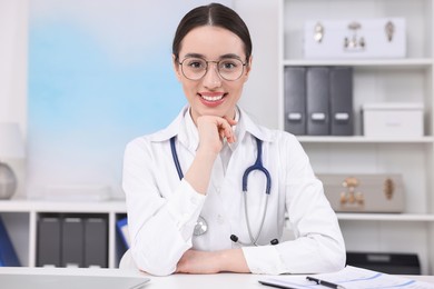 Photo of Medical consultant with stethoscope at table in clinic