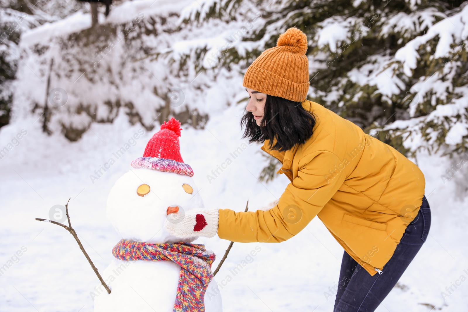 Photo of Happy woman making snowman outdoors. Winter vacation