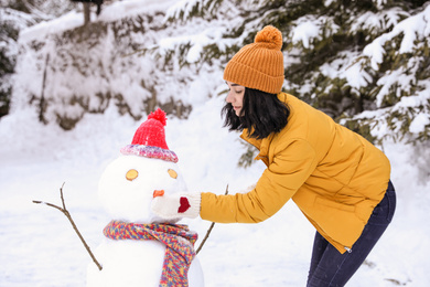 Happy woman making snowman outdoors. Winter vacation