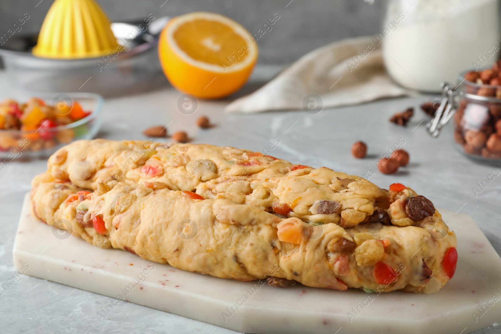 Photo of Unbaked Stollen with candied fruits and raisins on light marble table, closeup