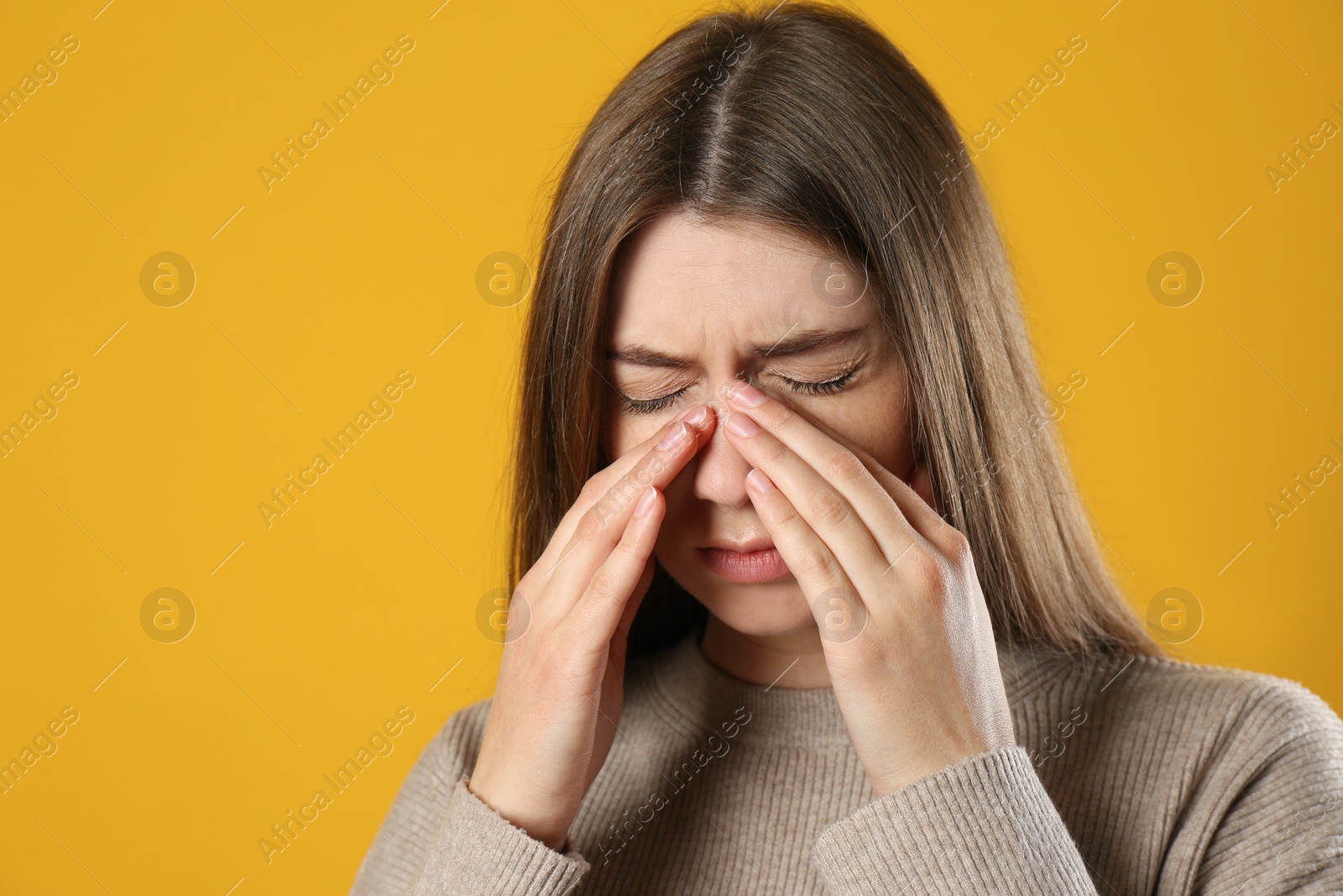 Photo of Young woman suffering from migraine on yellow background