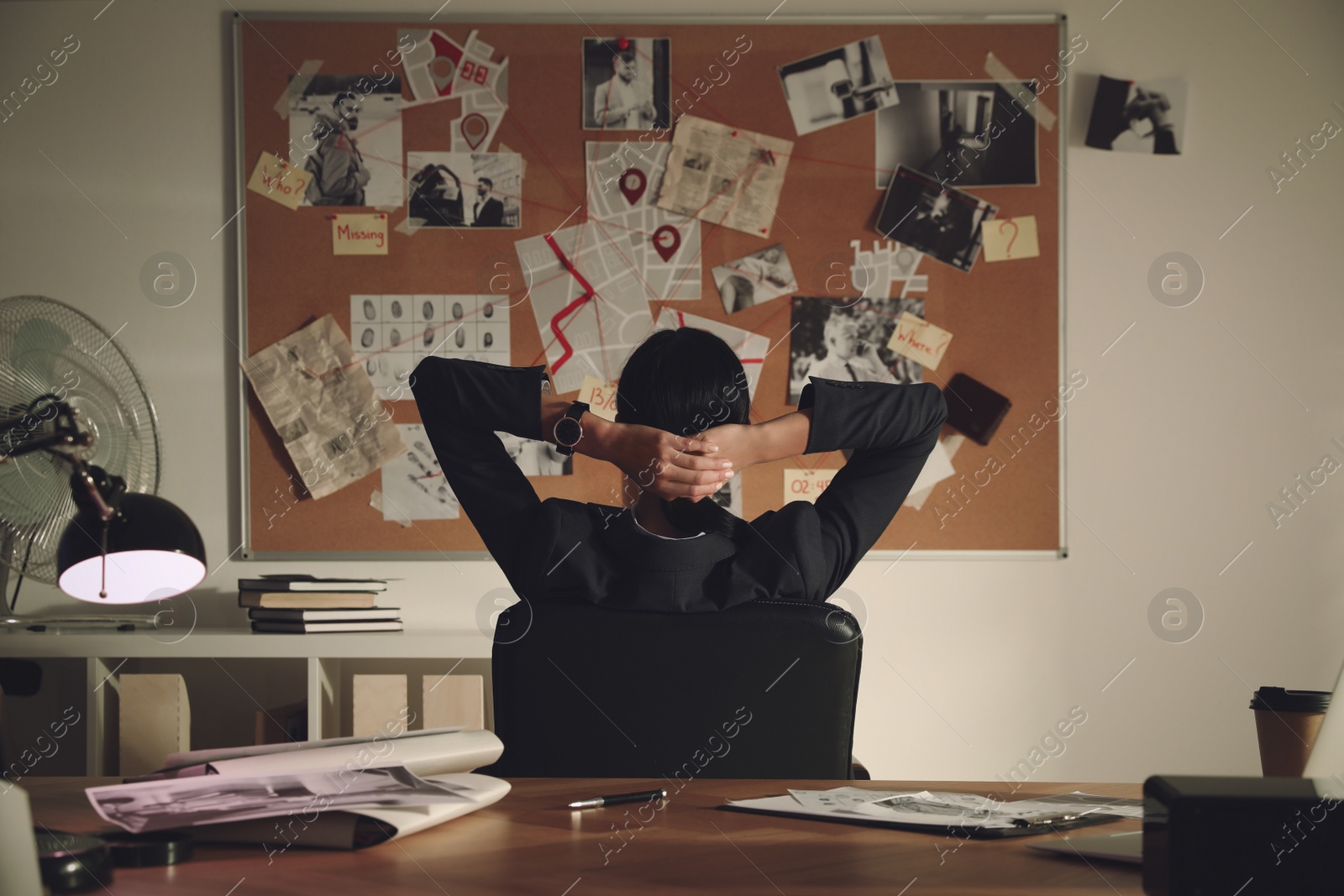 Photo of Detective looking at evidence board in office, back view