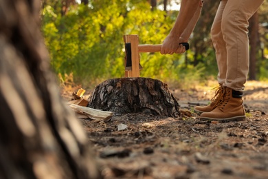 Man chopping firewood with axe in forest, closeup