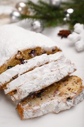 Traditional Christmas Stollen with icing sugar on white board, closeup
