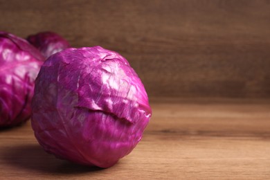 Photo of Whole ripe red cabbages on wooden table. Space for text
