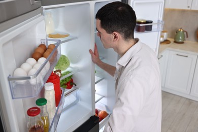 Man near refrigerator in kitchen at home