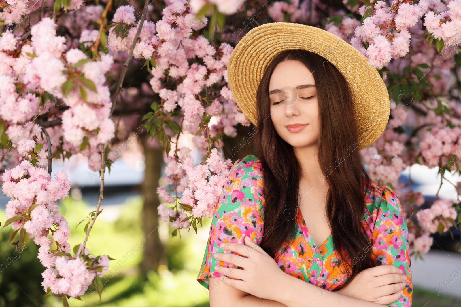 Photo of Beautiful woman in straw hat near blossoming tree on spring day