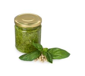 Photo of Delicious pesto sauce in jar, pine nuts and basil leaves isolated on white