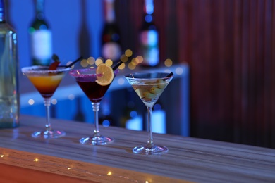 Photo of Different martini cocktails on table in bar, space for text