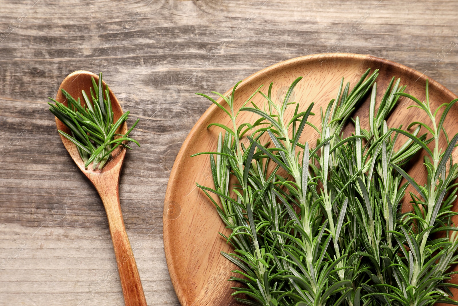 Photo of Fresh rosemary sprigs on wooden table, flat lay