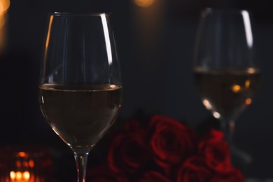 Photo of Glasses of white wine and rose flowers against blurred lights, space for text. Romantic atmosphere