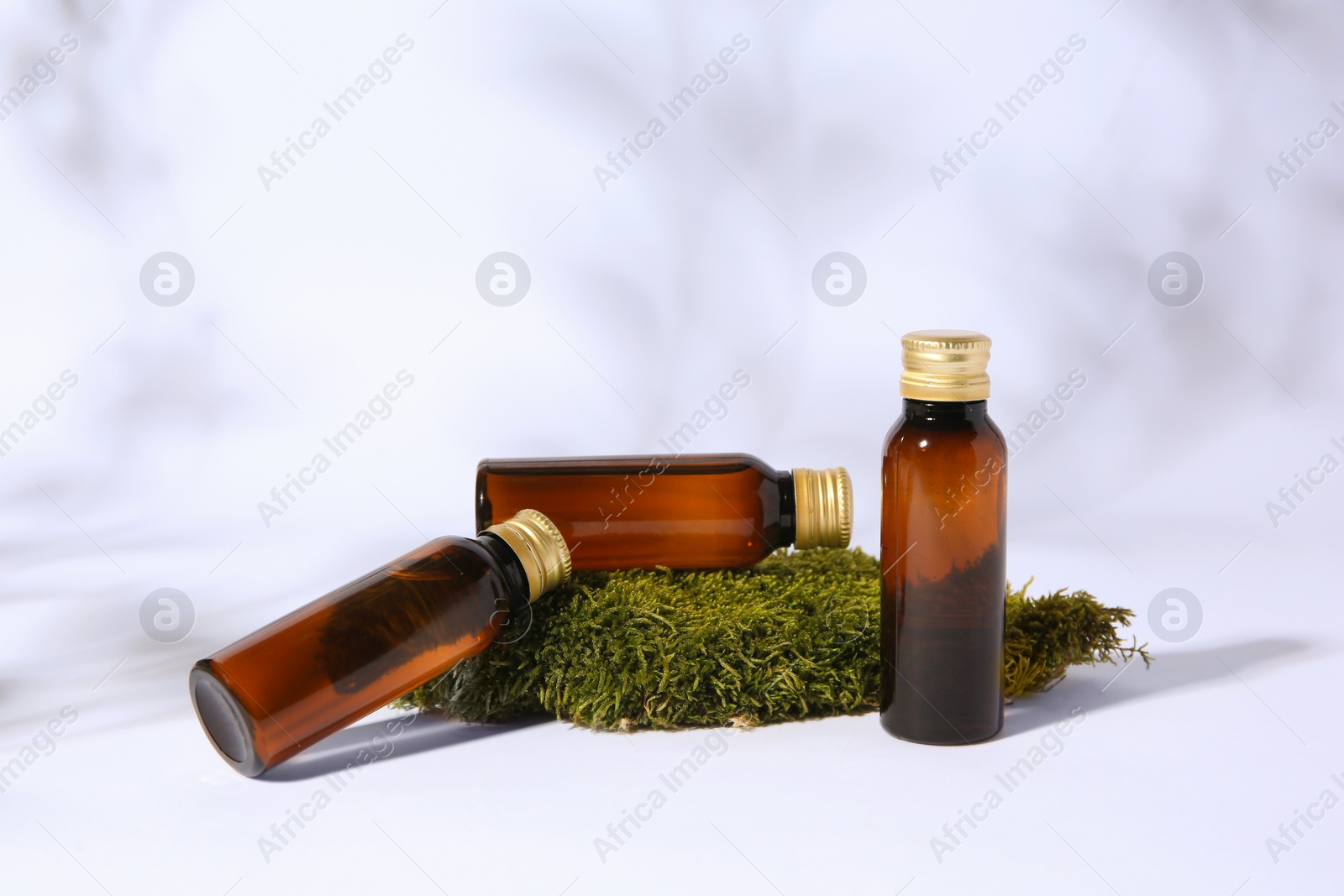 Photo of Bottles of cosmetic products and green moss on white background
