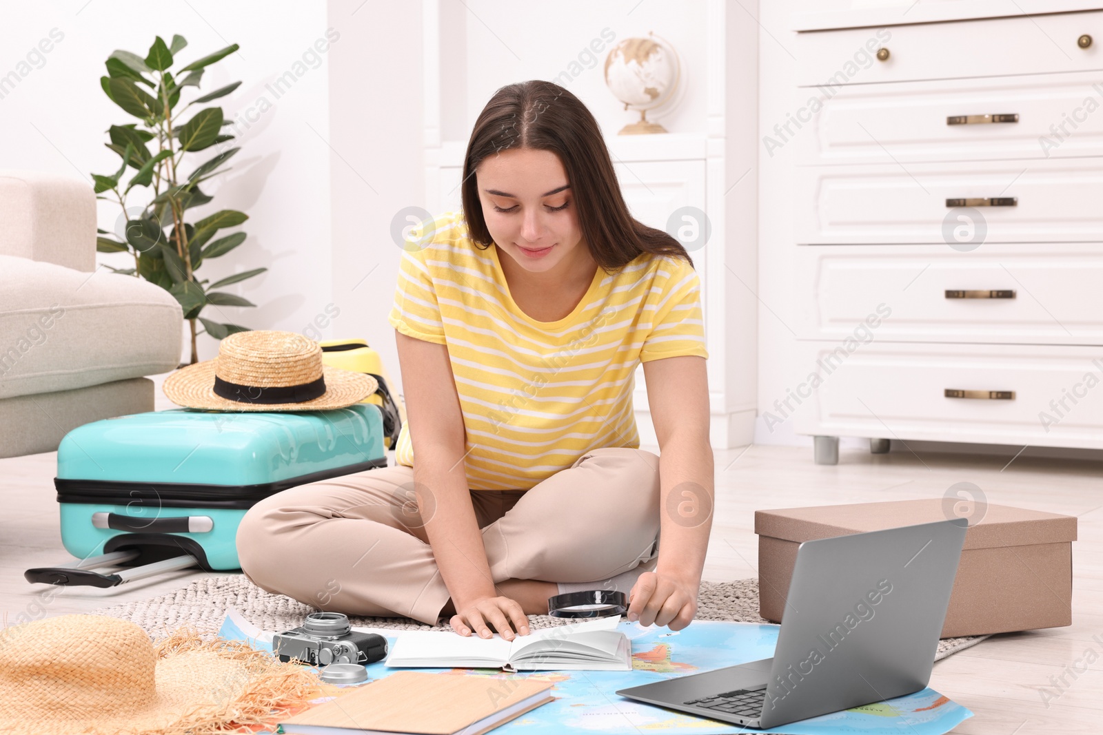 Photo of Travel blogger with magnifying glass and map planning trip at home