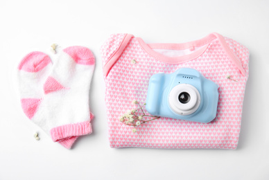 Photo of Composition with toy camera and children's clothes on white background, top view. Future photographer