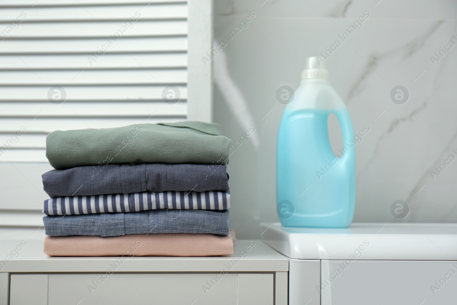 Photo of Fresh clean laundry and detergent in bathroom