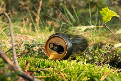 Photo of Used aluminium can on green grass outdoors. Recycling problem