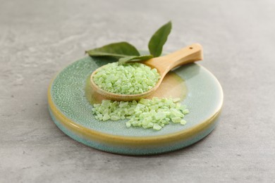 Photo of Aromatic sea salt and green leaves on grey textured table