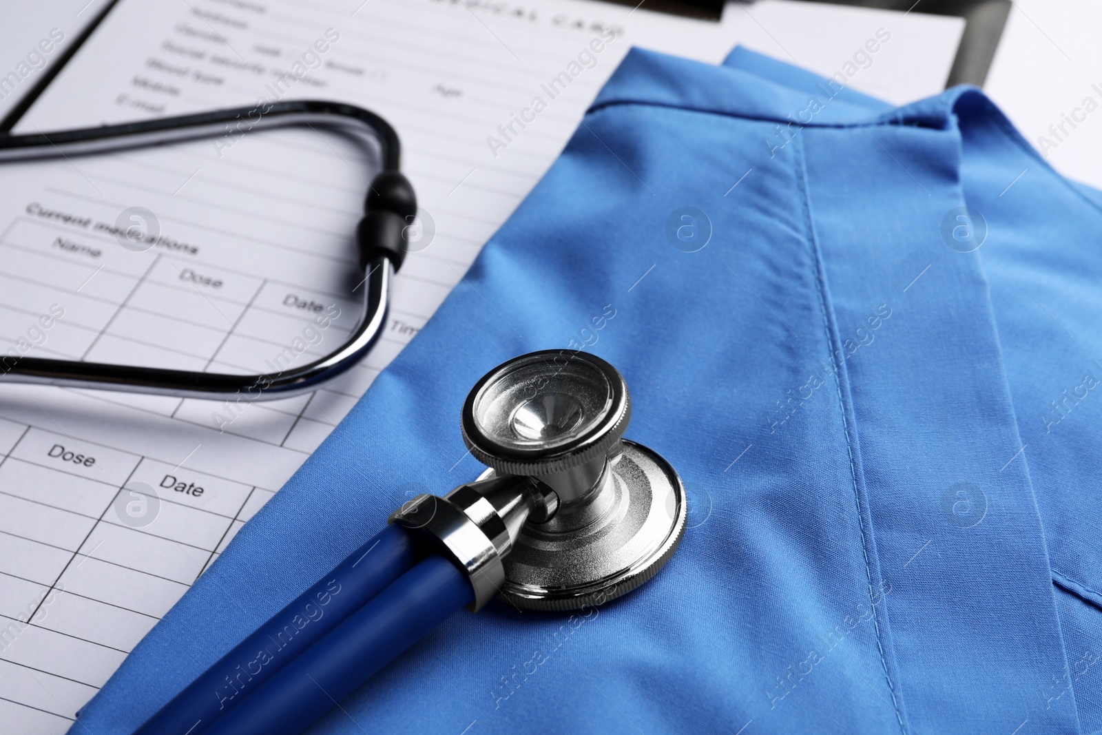 Photo of Medical uniform, stethoscope and documents, closeup view