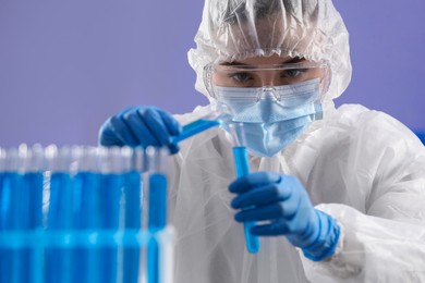 Scientist holding test tubes with light blue liquids in laboratory