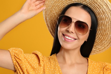 Photo of Beautiful woman wearing sunglasses on yellow background, closeup