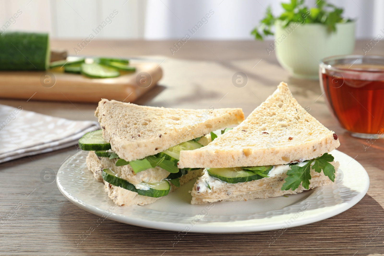 Photo of Plate with traditional English cucumber sandwiches on table