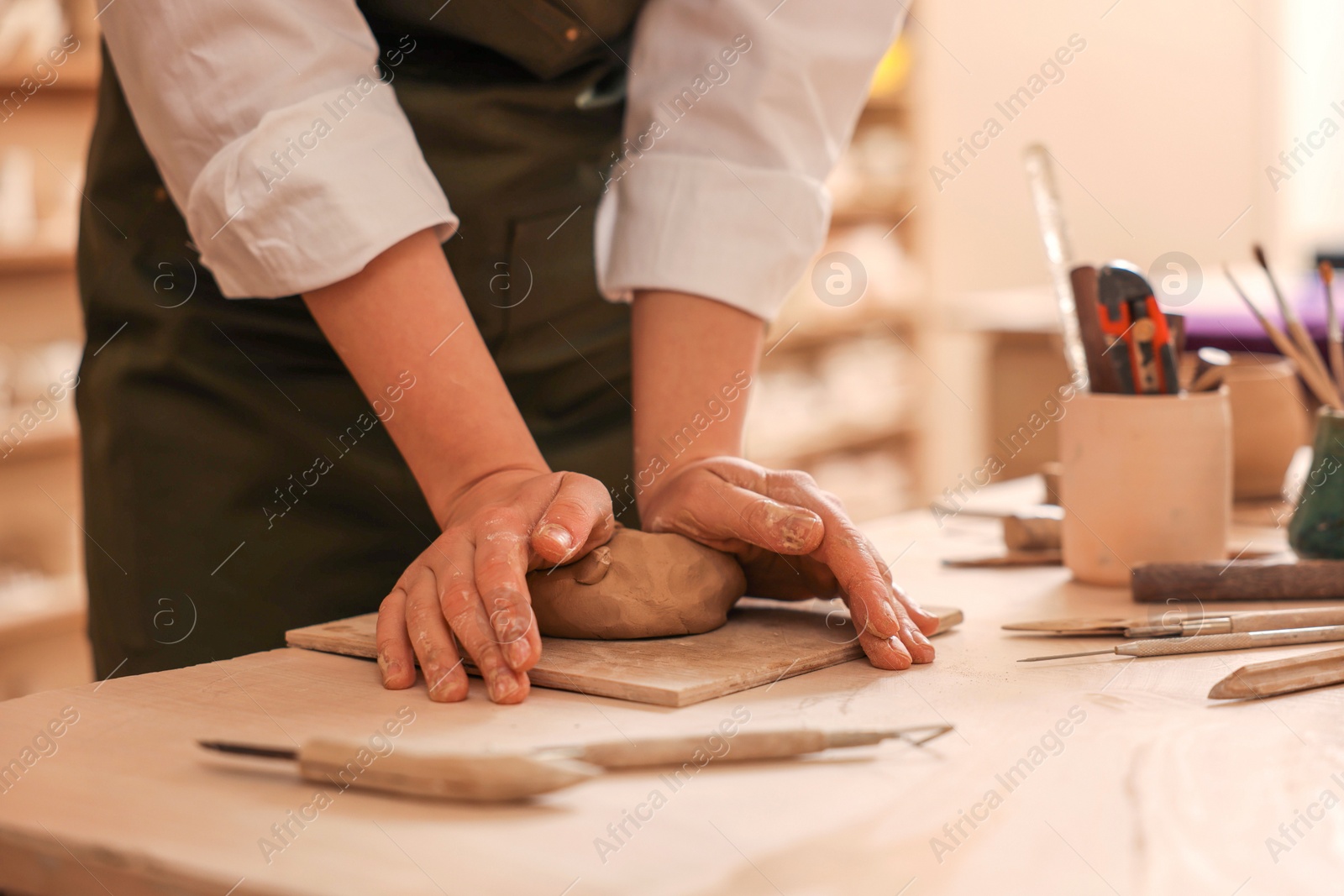 Photo of Woman crafting with clay at table indoors, closeup