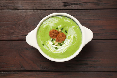 Tasty homemade zucchini cream soup on wooden table, top view