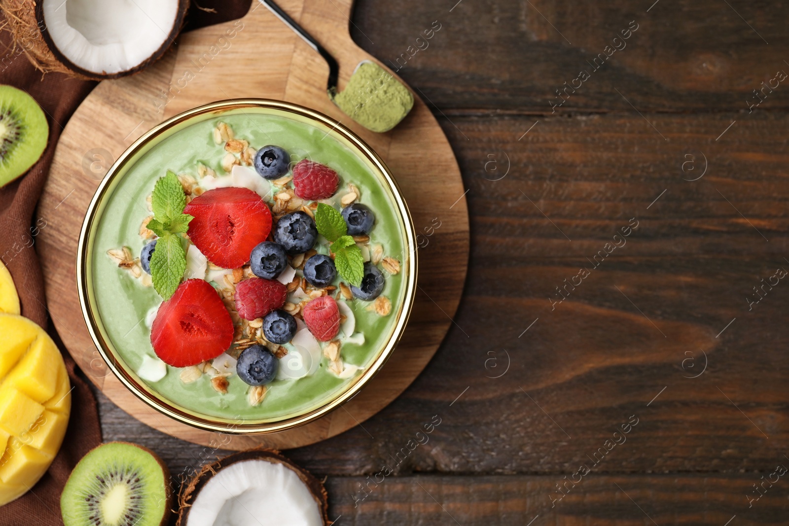 Photo of Tasty matcha smoothie bowl served with fresh fruits and oatmeal on wooden table, flat lay with space for text. Healthy breakfast