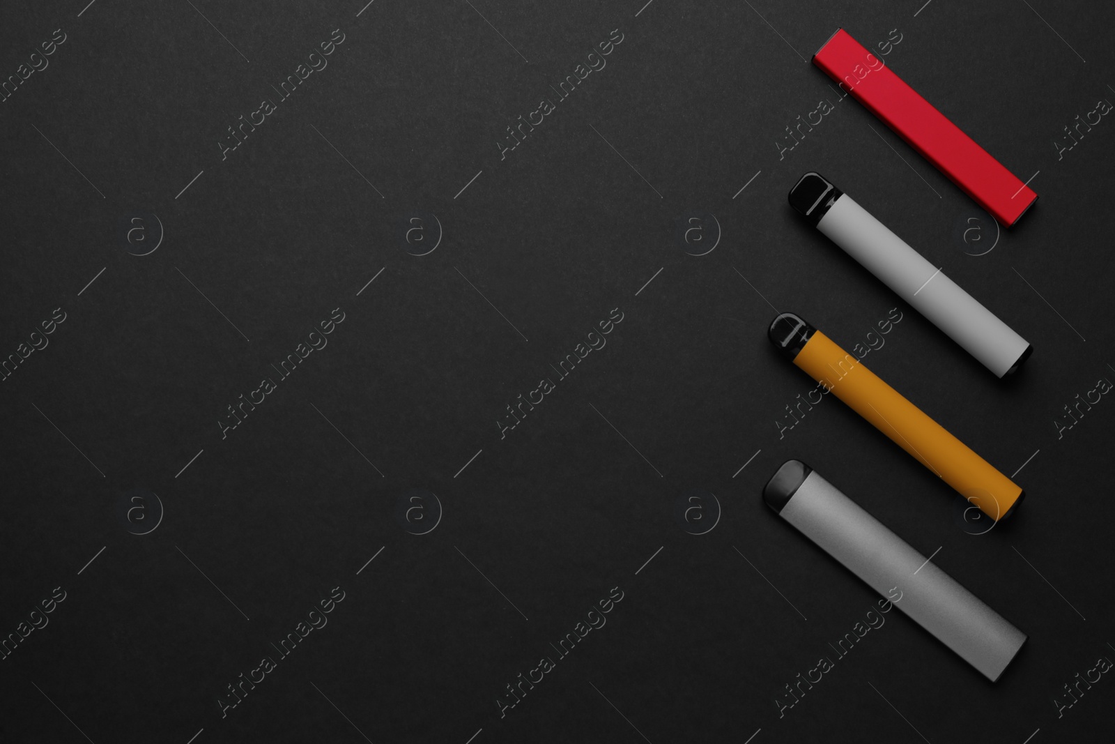 Photo of Disposable electronic smoking devices on black background, flat lay. Space for text