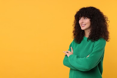 Happy young woman in stylish green sweater on yellow background, space for text