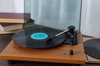 Photo of Retro turntable with vinyl record on wooden table