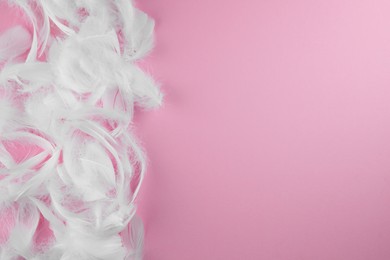 Photo of Many fluffy white feathers on pink background, flat lay. Space for text
