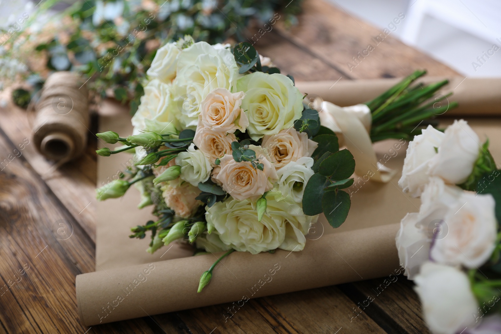 Photo of Beautiful wedding bouquet and paper sheet on wooden table, closeup