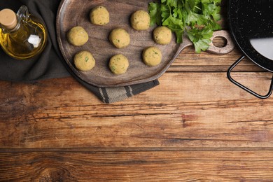 Photo of Raw falafel balls and ingredients on wooden table, flat lay. Space for text