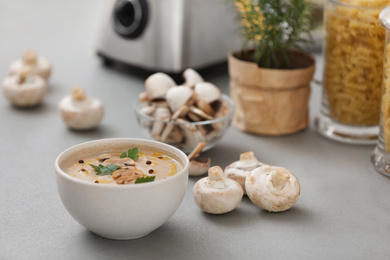 Photo of Delicious cream soup with mushrooms on grey table