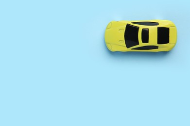 One yellow car on light blue background, top view with space for text. Children`s toy