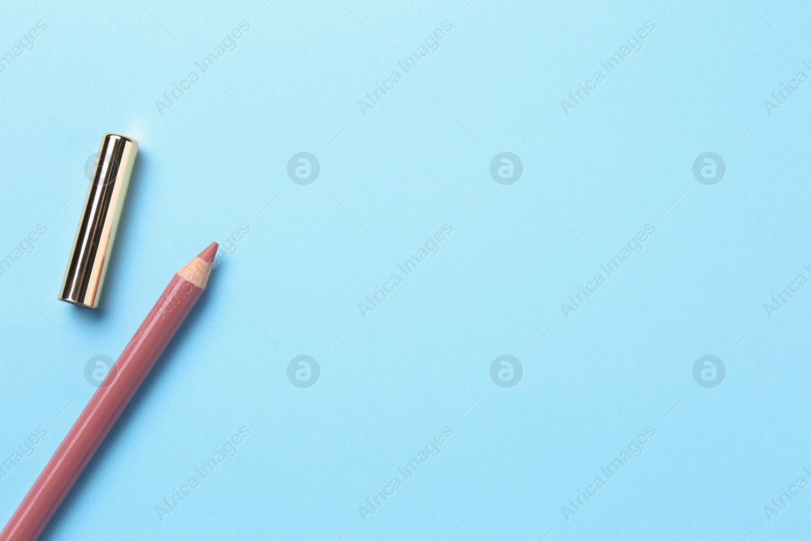 Photo of Lip pencil on light blue background, flat lay with space for text. Cosmetic product
