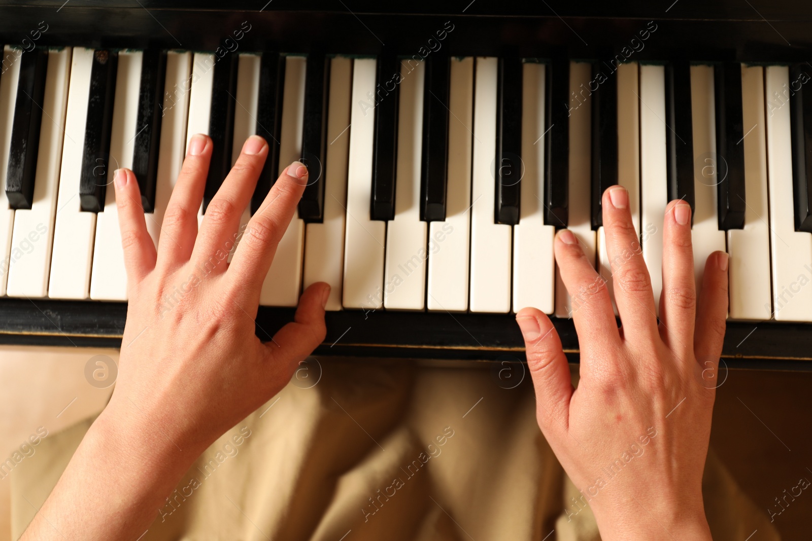 Photo of Young woman playing piano, above view. Music lesson