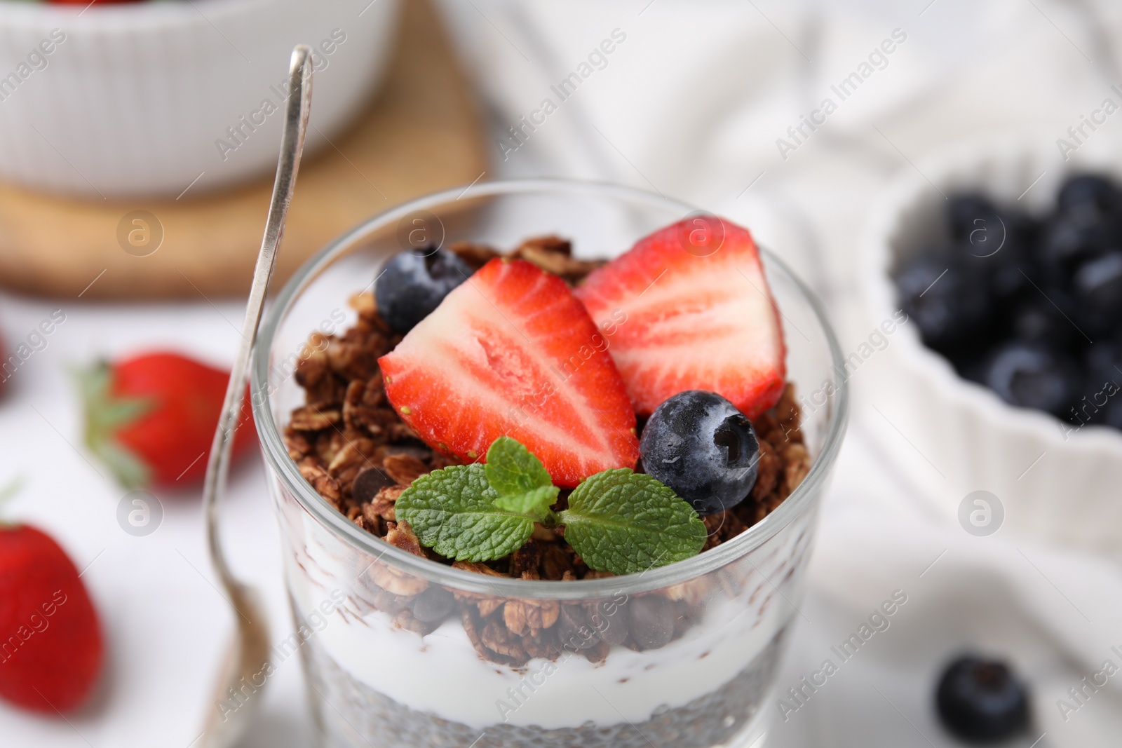 Photo of Tasty granola with berries and yogurt in glass on table, closeup