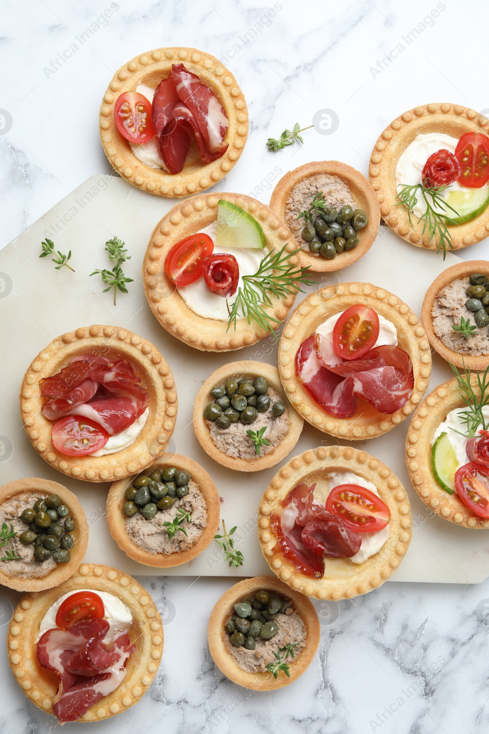 Photo of Different delicious canapes on white marble table, flat lay