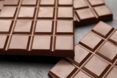Photo of Delicious milk chocolate bars on black table, closeup