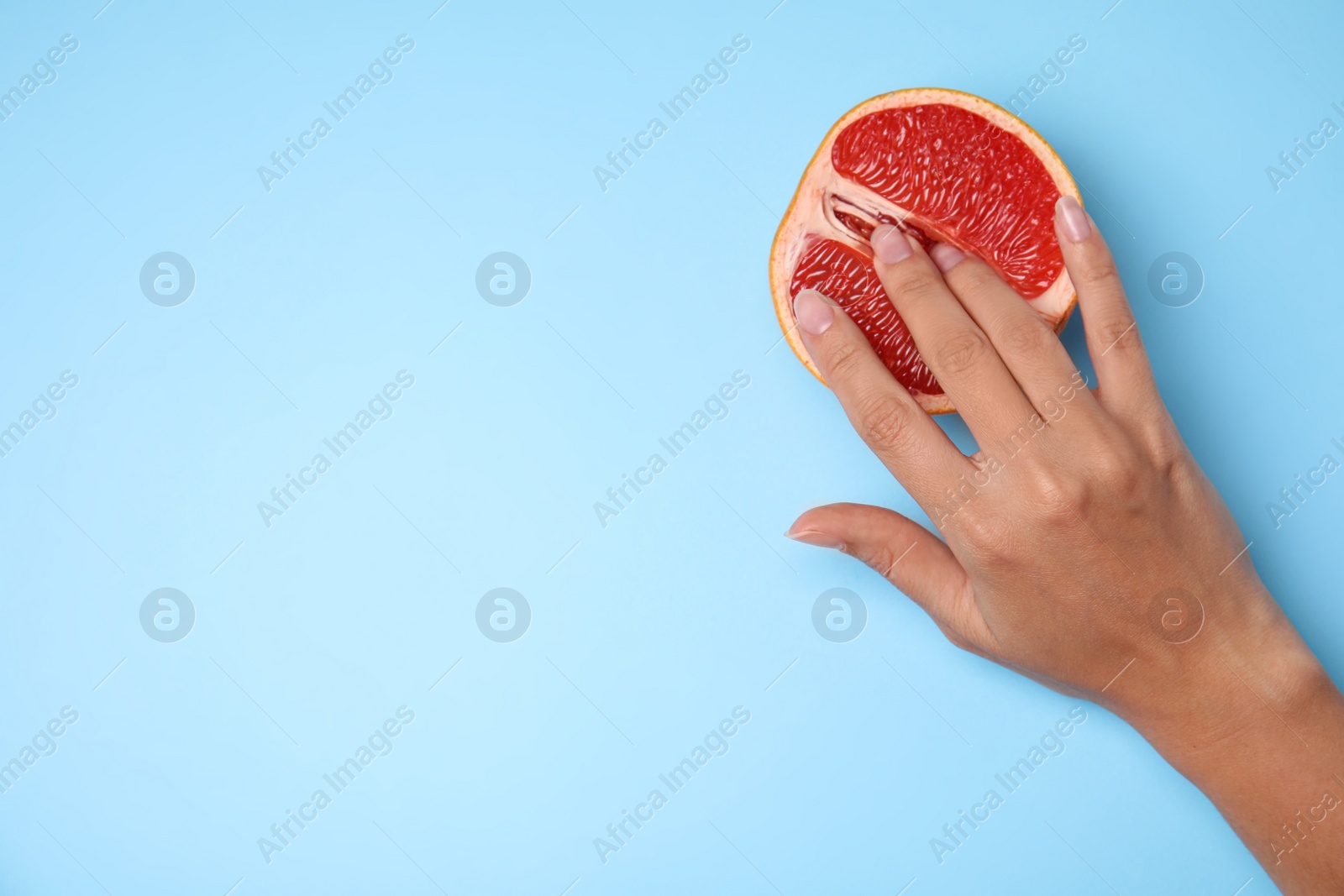 Photo of Young woman touching half of grapefruit on blue background, top view with space for text. Sex concept