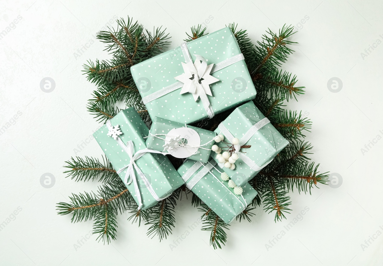 Photo of Christmas gift boxes with fir branches on white background, flat lay