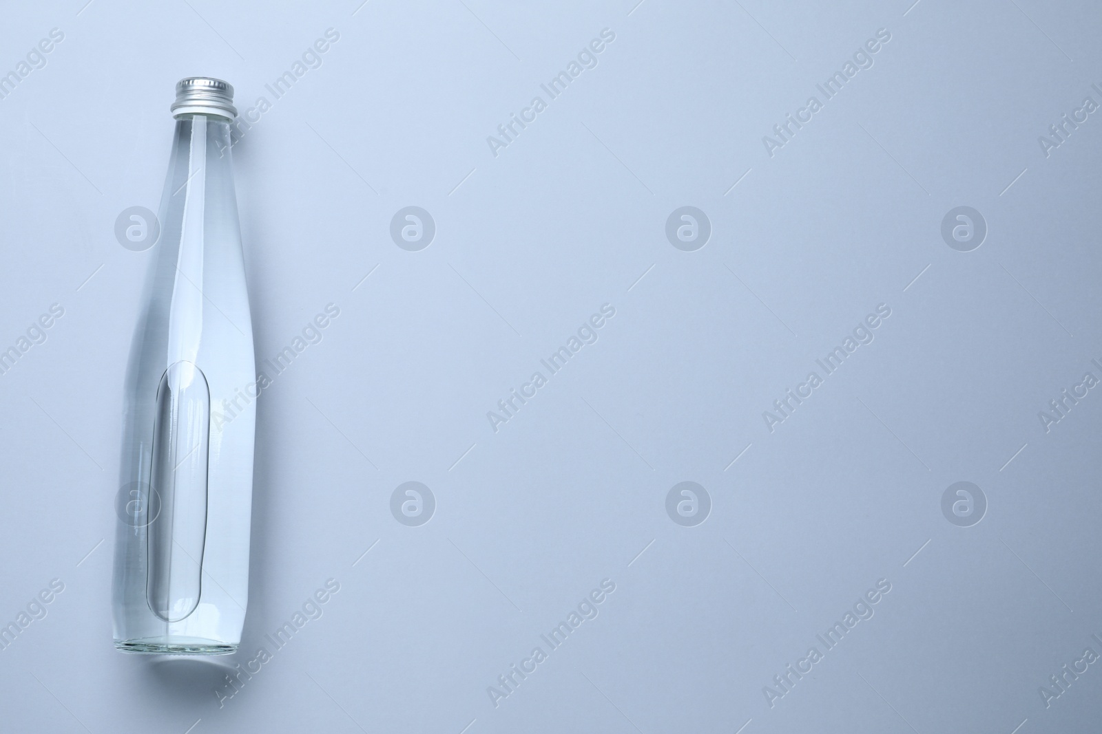 Photo of Glass bottle with water on white background, top view. Space for text